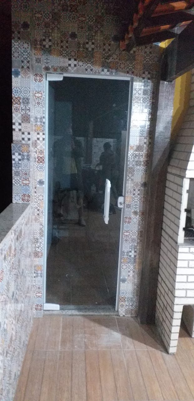 Porta de vidro instalada em área externa com churrasqueira